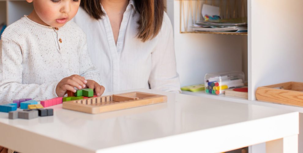 Kid playing with a tetris wood puzzle and mother or teacher help